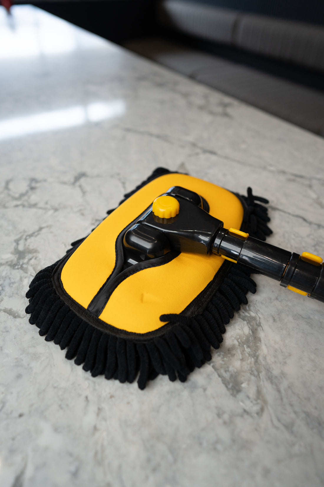 Close up of the car wash mop head, yellow backing plate with black chenille strands