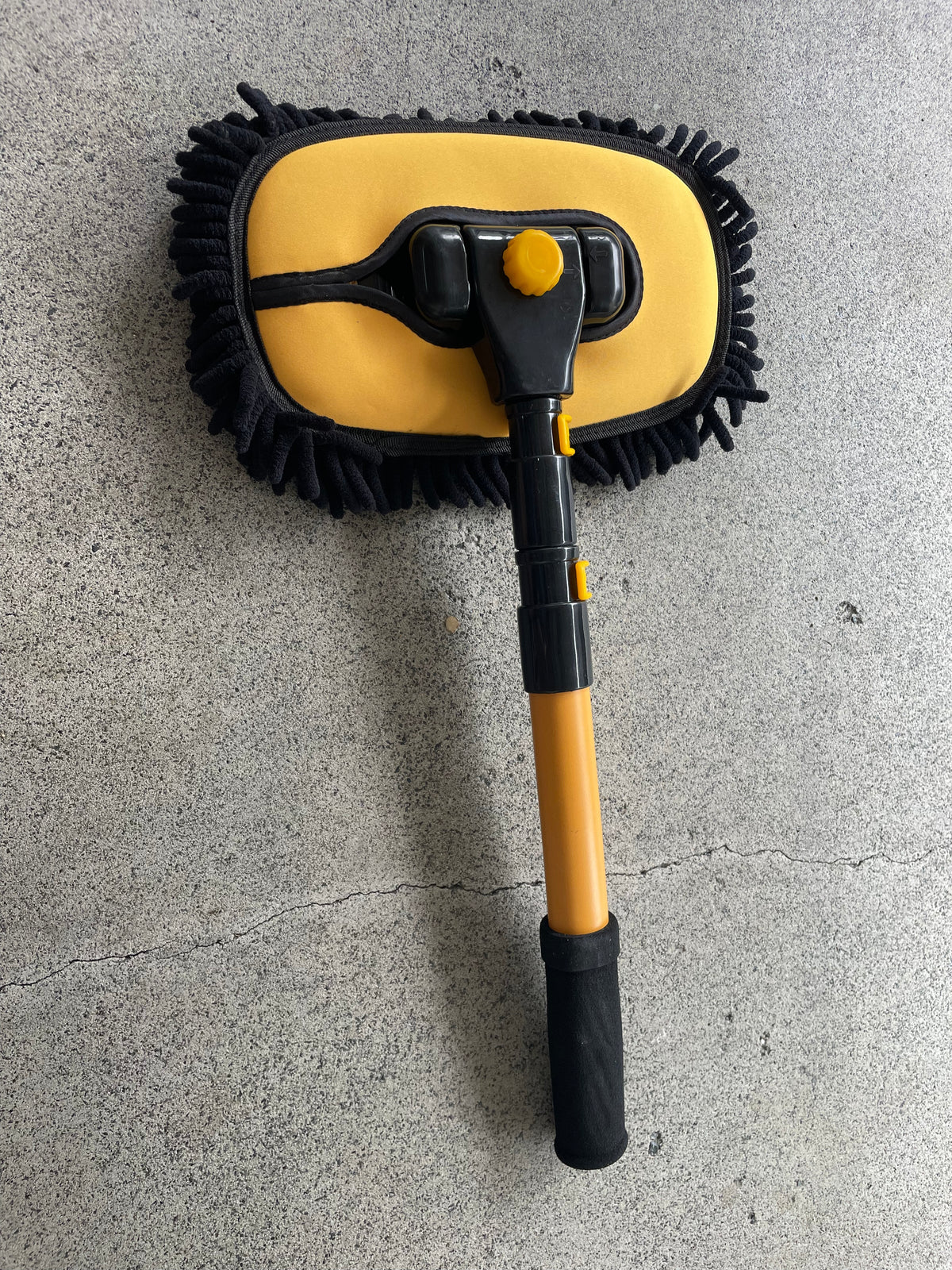 Car wash mop head with yellow backing plate and black chenille strands, pole collapsed