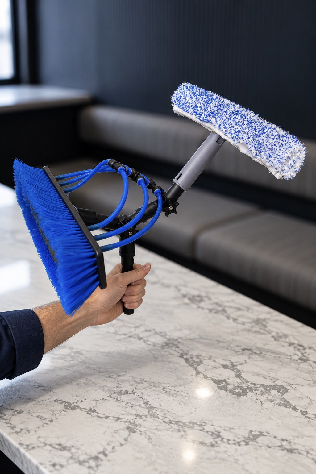 Hand holding a pole adapter fitted with the swivel T-bar window washer and blue water fed pole brush