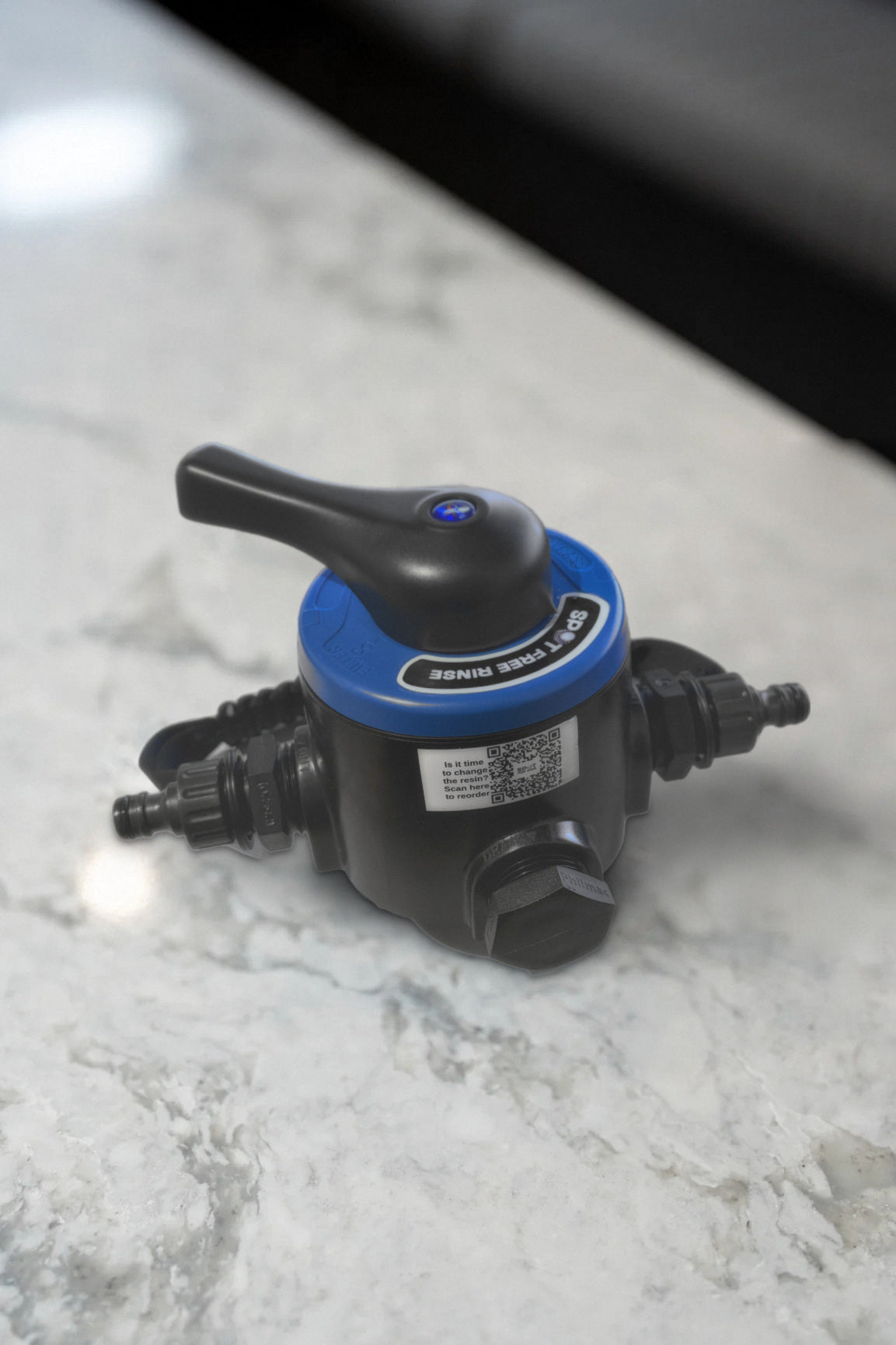 Spot Free Rinse tank head with bypass on a marble bench, showing the bypass lever, inlet and outlet fittings and the resin reorder QR label