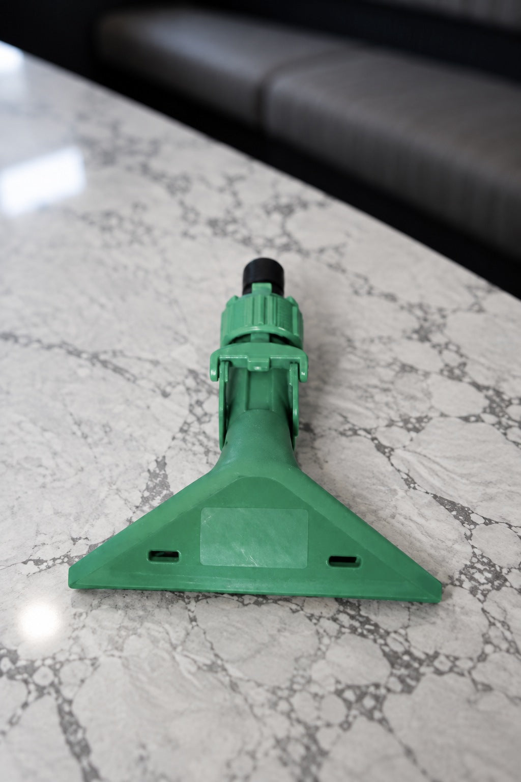 Face of the green Fixi clamp lying flat, showing the jaw, collar and black threaded adapter