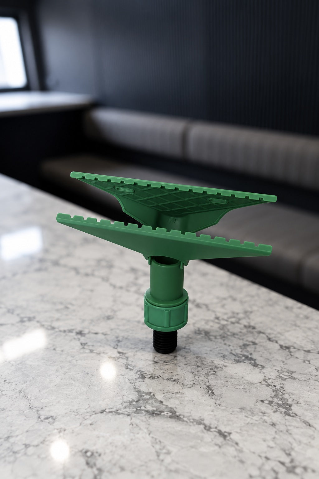 Green Fixi clamp for a water fed pole with its jaws open, standing on its black threaded adapter